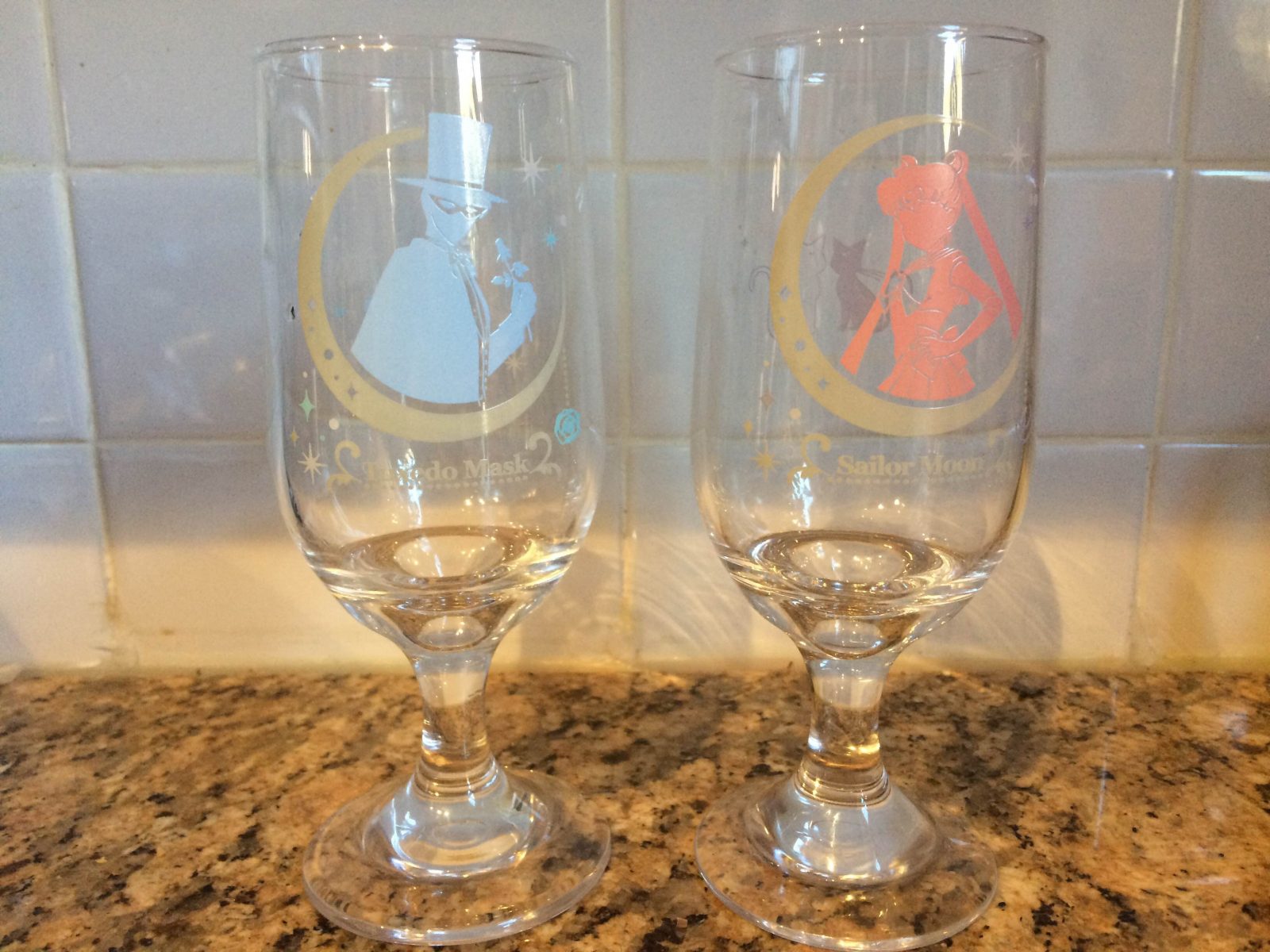 two wine glasses one with the blue tuxedo mask and another with a pink sailor moon