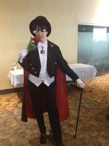 A woman stands in Tuxedo Mask cosplay