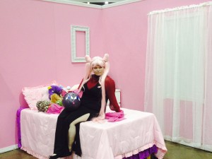 Black Lady sits on a bed in a pink bedroom