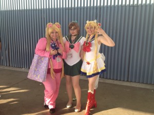 A cosplaying Usagi in pjs, holding a plush Luna, Super Sailor Jupiter and Super Sailor Moon pose for the camera