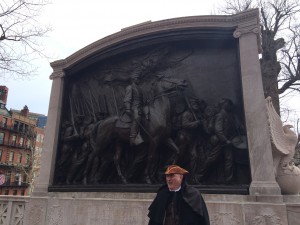 A white man dressed in period clothing stands in front of the monument of the 54th