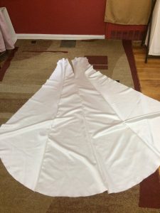 three panels of an ivory dress laying on the floor