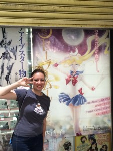 A young white woman poses infront of a huge sailor moon manga poster on a store window