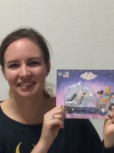 A young white woman holds a package with two Sailor Jupiter charms