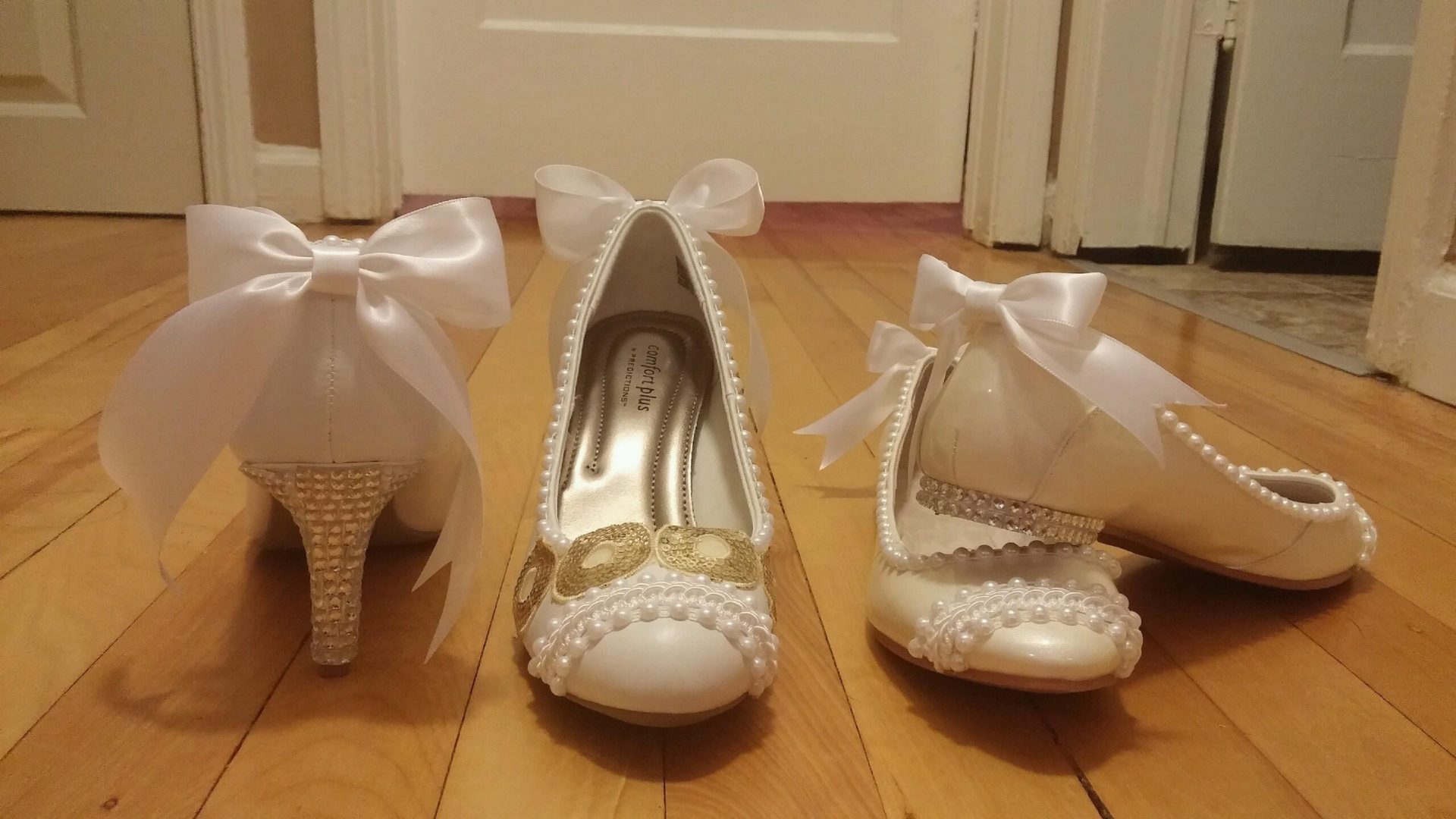 two sets of white shoes one with heels and another flats with pearls and white bows