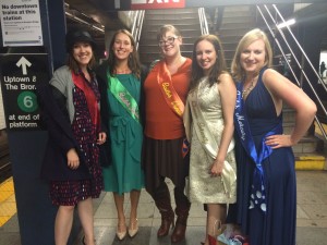 Five young women stand in sailor guardian colors at a train station