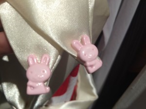 A cream sash with two cute little pink plastic bunnies at the ends