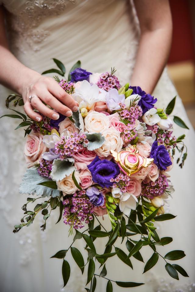 a pink and purple wedding bouquet with a crisis brooch in it.