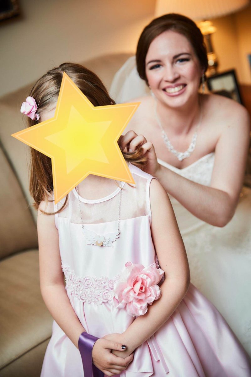 a bride fixes a necklaces on a young flower girl wearing pink