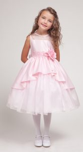 a little white girl stands wearing a pink layered flower girl dress