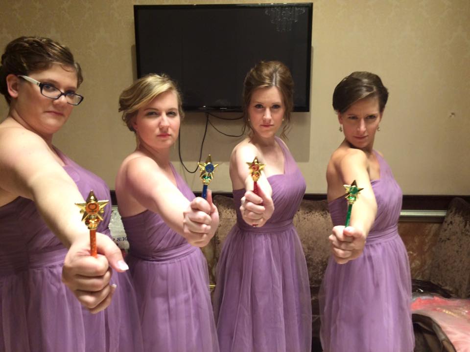 four young women in purple dresses looking very serious with transformation wands